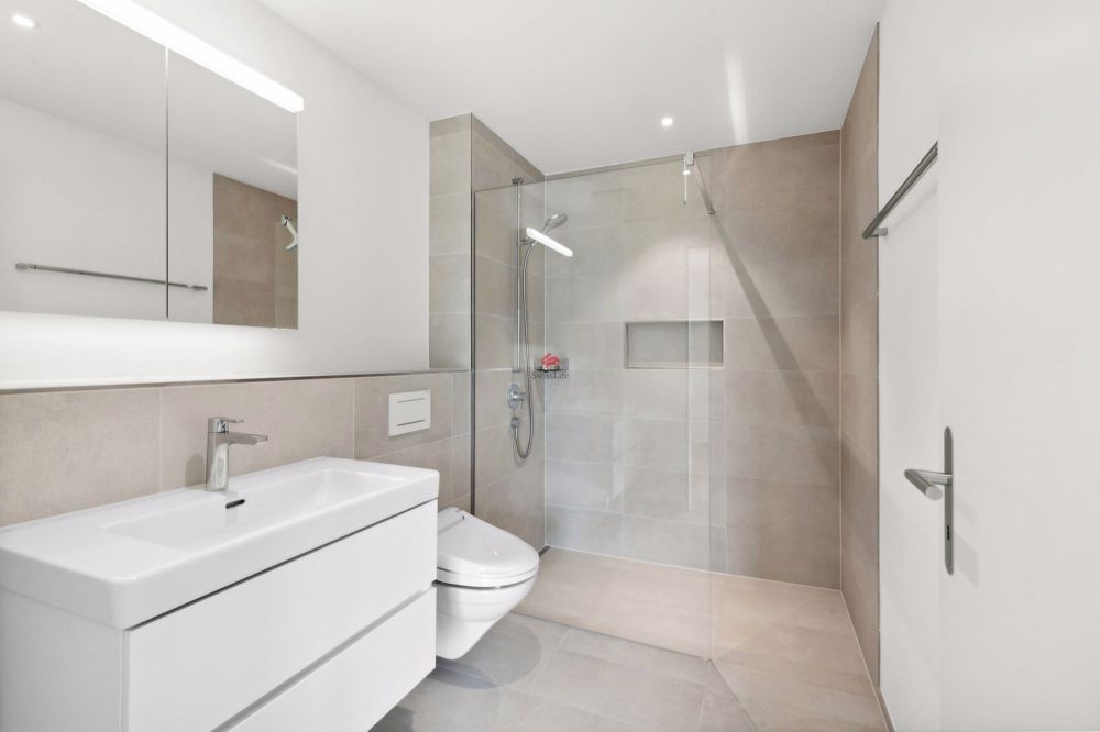 Das moderne Bad en Suite mit Geberit Dusch-WC und barrierefreier Dusche.