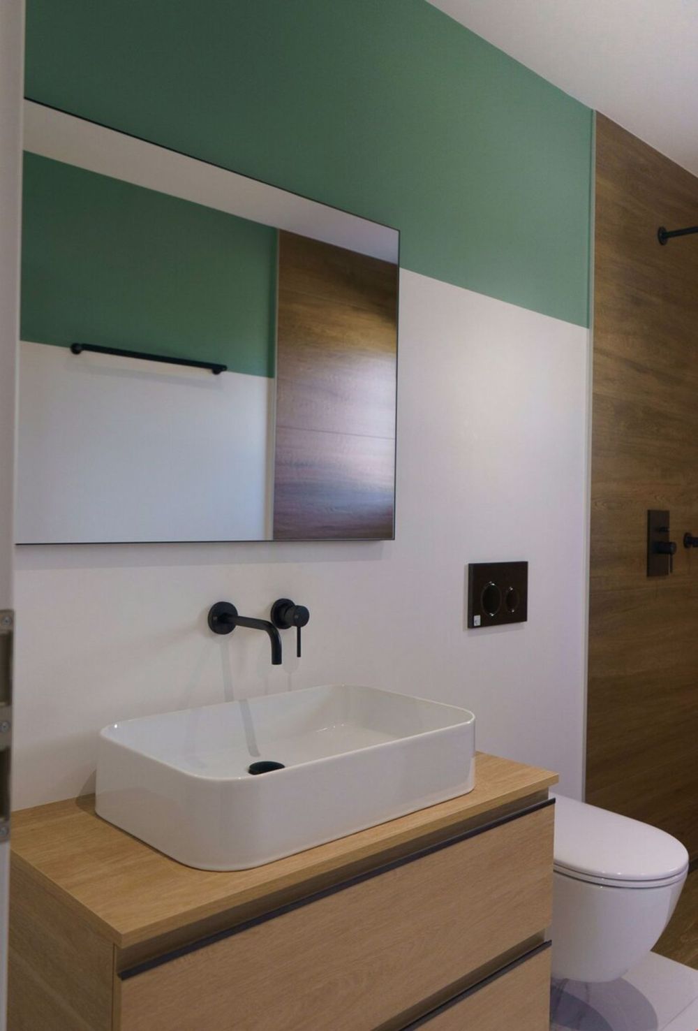 une salle de bains aux murs verts avec un lavabo et des toilettes blancs / a bathroom with green walls and a white sink and toilet